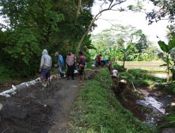 Bhabinkamtibmas Bantu Warga Gotong Royong Melaksanakan Pelebaran Jalan Desa